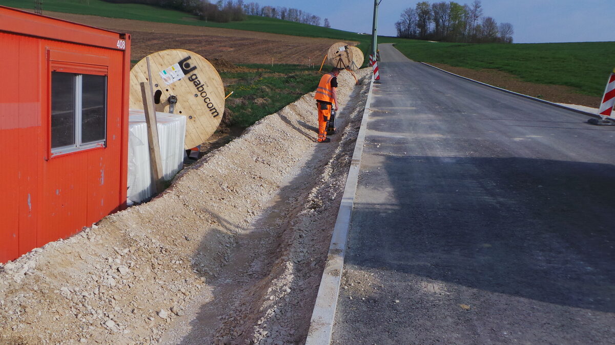 Straßenbaustelle mit offenem Graben und Arbeitsteam